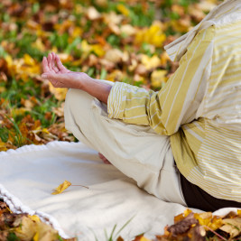 Idosa sentada em parque praticando a yogaterapia