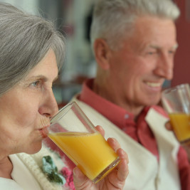 mulher e homem idosos com boa deglutição bebendo suco de laranja