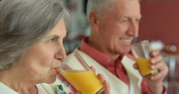 mulher e homem idosos com boa deglutição bebendo suco de laranja