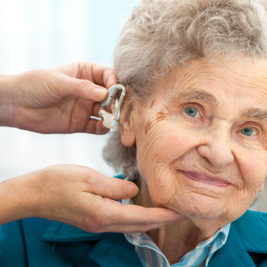 idosa com problemas de audição usando aparelho auditivo