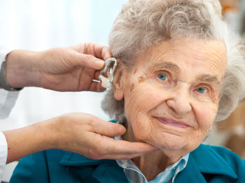 idosa com problemas de audição usando aparelho auditivo